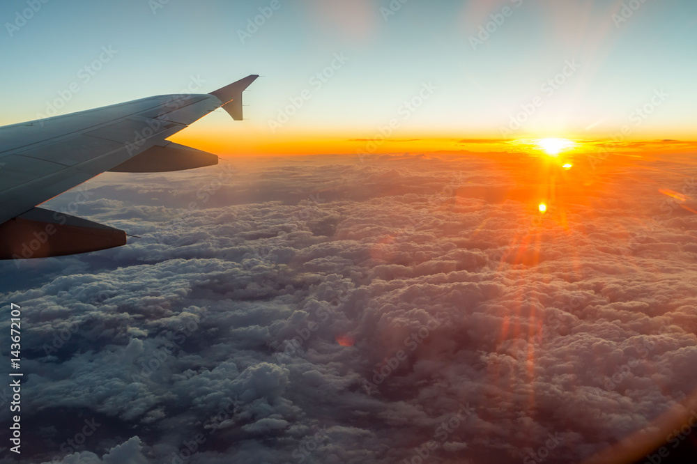 Fototapeta premium sunset from the window above the clouds with airplane wing