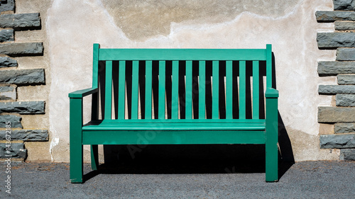 Green wooden bench set against a concrete wall with stone decorations taken at Grey Towers National Historic Site in Milford, Pennsylvania