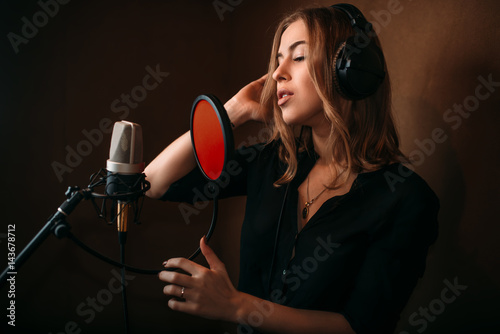 Female singer recording a song in music studio