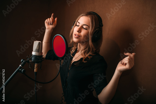 Valokuva Woman vocalist in headphones against microphone