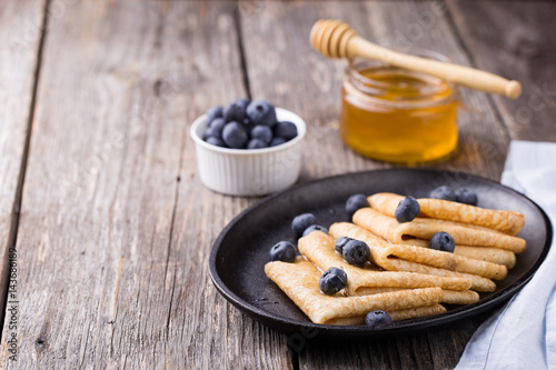 Crepes with honey on wooden background
