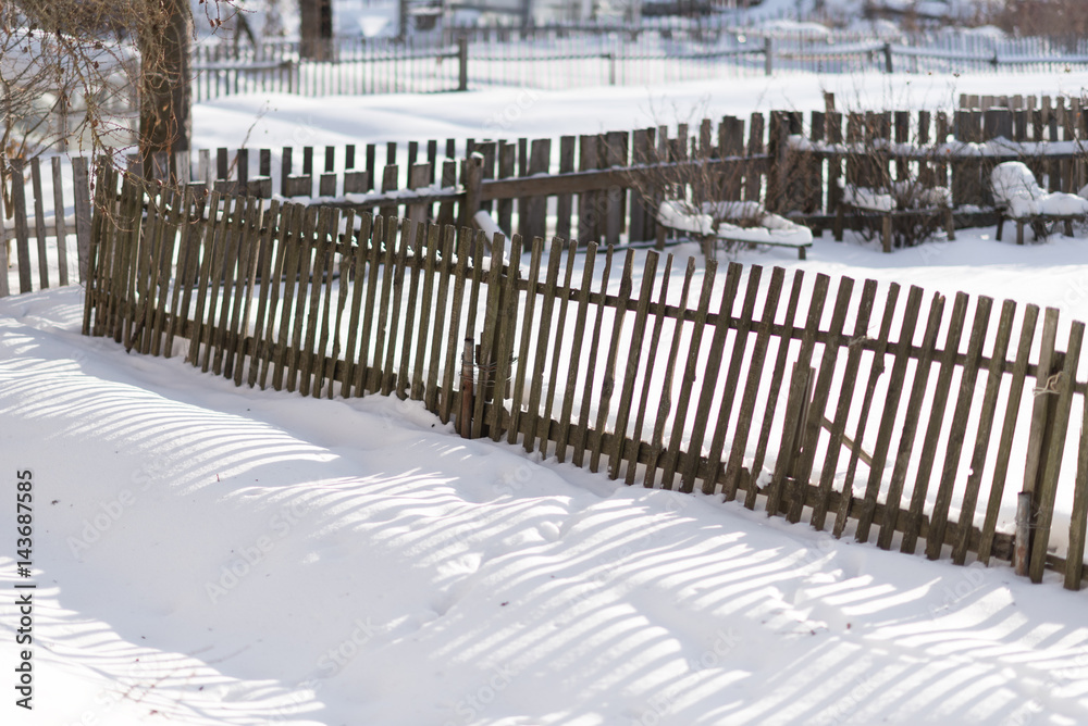 Slope of an old fence in the snow in the winter clear day
