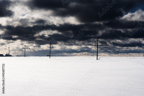 field of snow with electric poles and cloudy sky © Mak