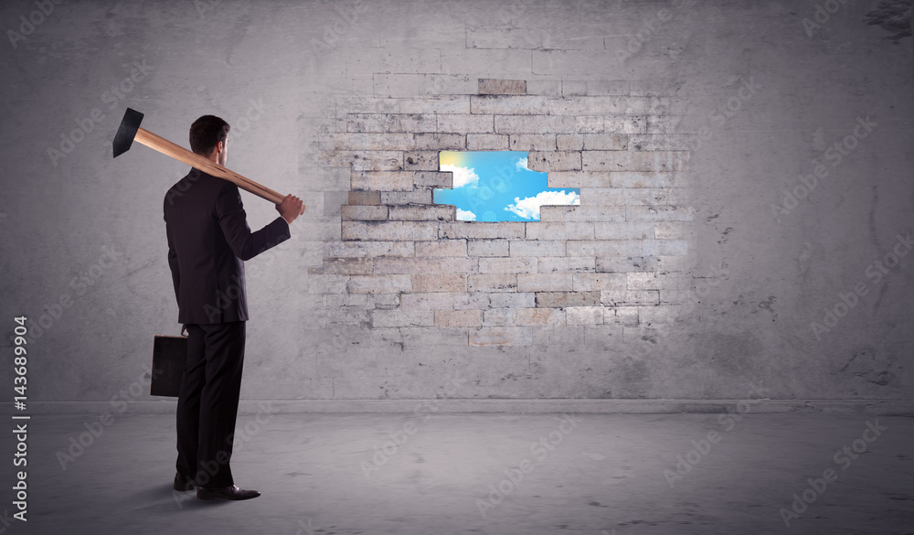 Business man hitting brick wall with hammer Business man hitting brick wall with hammer
