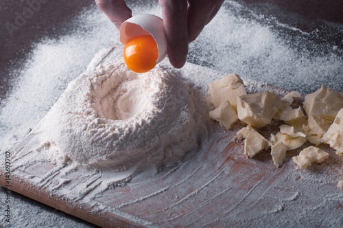 Douth, food, cooking concept - preparing douth - cooking progress and ingridients, Chef pours egg yolk from eggshell into flour photo