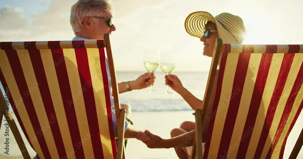 Happy retired couple enjoying beautiful sunset at the beach