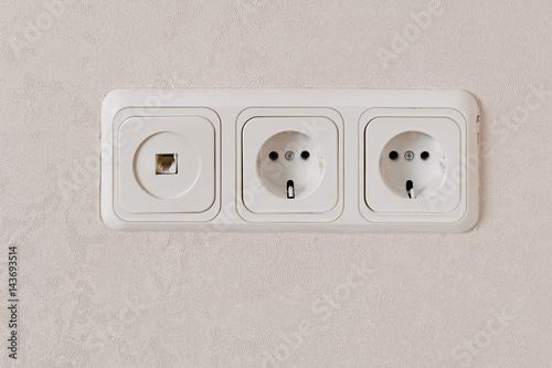 Two electric outlets on wall EU standart and telephone plug.