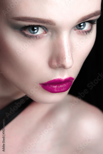 Portrait of beautiful girl model with pink lips and blue eyes with leather belt on her neck, fresh clean highlighted skin. Fashion retouched close up shot.