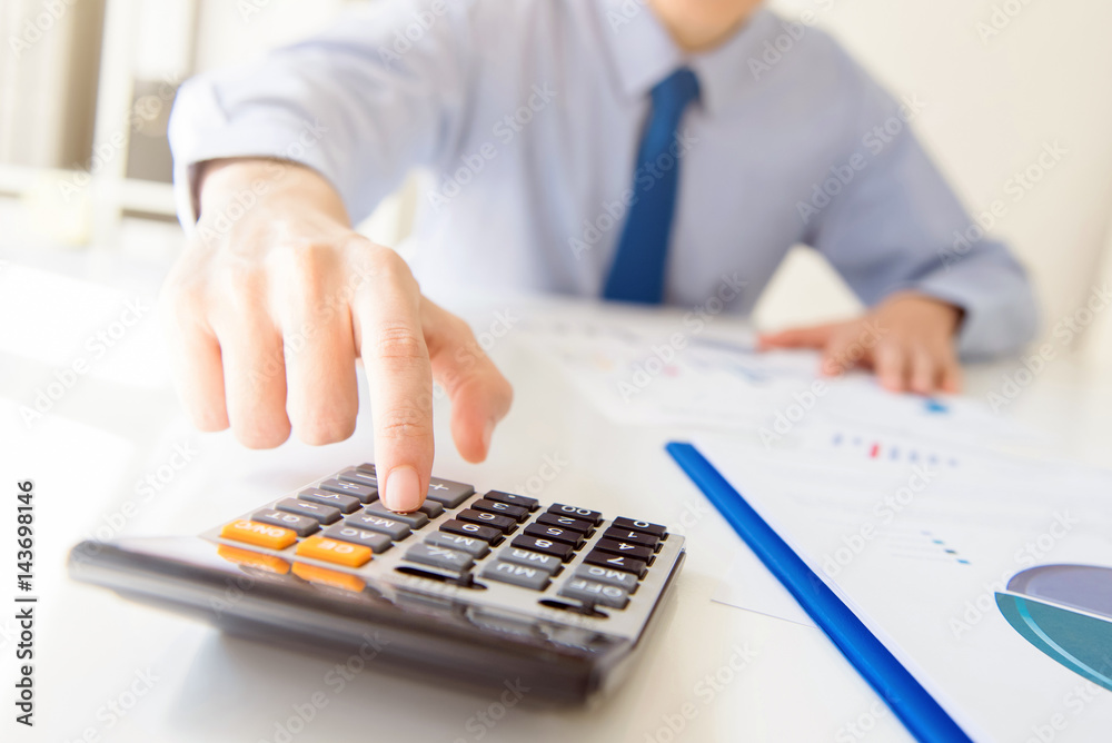 Fototapeta premium Businessman pressing calculator button at working table in the office