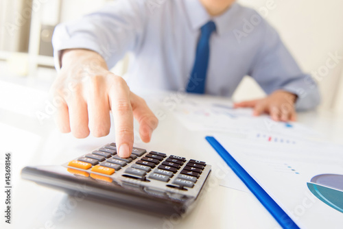 Businessman pressing calculator button at working table in the office