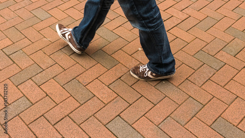 Men's legs and feet, walking on a brick paved area