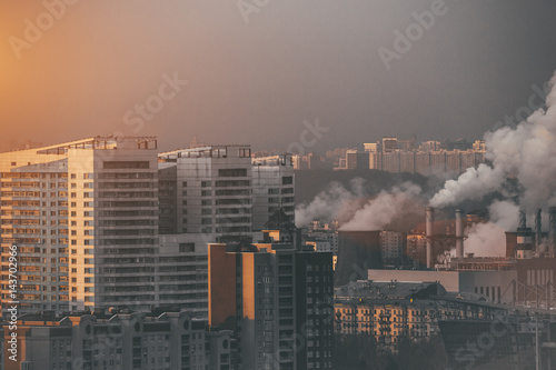 Close-up shooting from high point of metropolitan city  residential buildings and districts illuminated by morning sun  smoke and chimneys of combined heat and power plant polluting environment