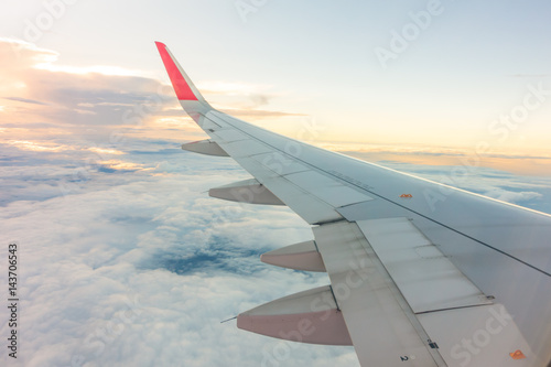 Wing of an airplane flying above the clouds .