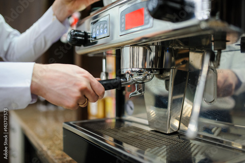 Closeup of a man barista brewing an espresso using a coffee machine