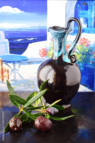 Traditional Greek ceramic olive oil jar with lemon, sea salt, olives, brunch of olive tree on a dark back ground. photo