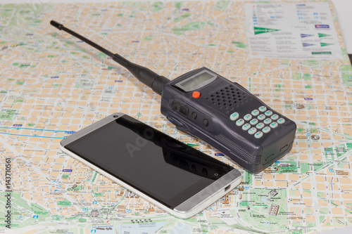 Walkie-talkie and smartphone lie on the map