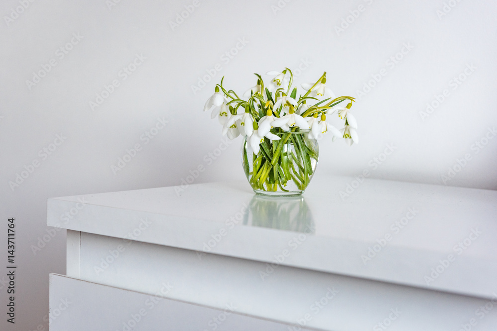 spring flowers in a vase on light table in white room