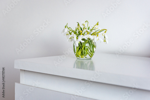 spring flowers in a vase on light table in white room