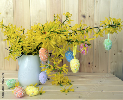 Easter color eggs are a holiday symbol. Eggs are located on branches of the blossoming forzition. Decorative bouquet. photo