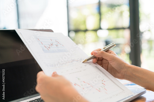 Business woman hand with Financial charts and laptop on the table .