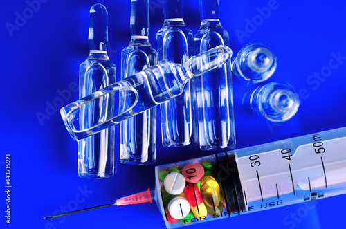 Syringe for subcutaneous injections with glass ampoules and multicolored tablets on an isolated background. Ampoule. Syringes