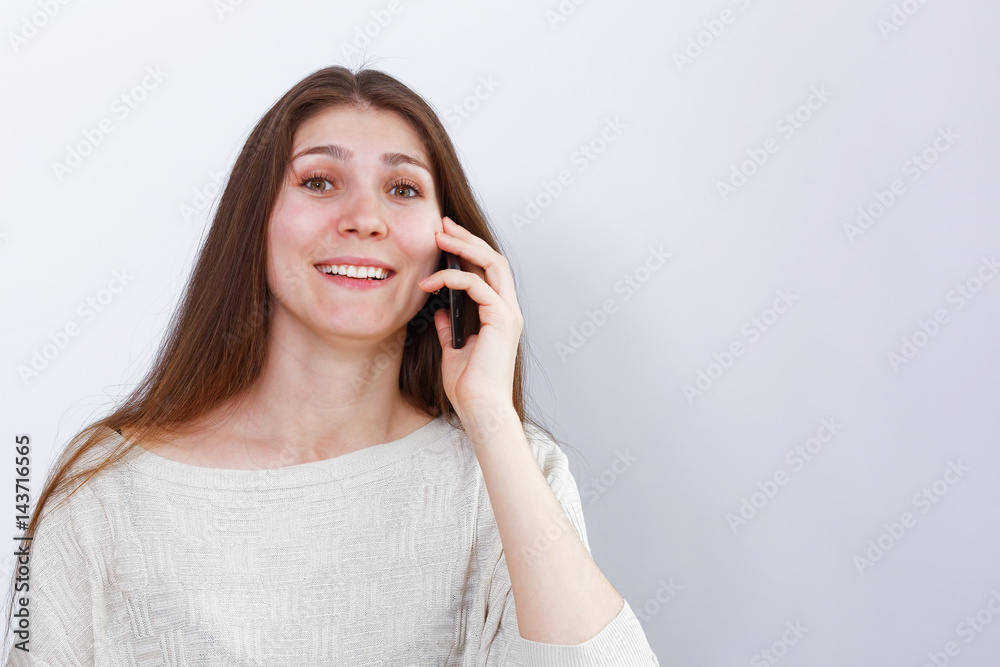 Portrait of young happy woman talking on the phone.  Human reaction, expression. Grey background.