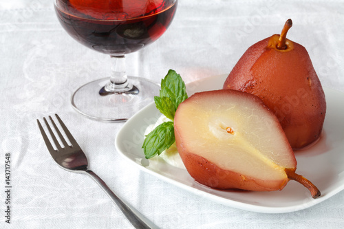 Dessert with pear stewed in wine sauce on the background of a glass of wine. French. Home-cooked food