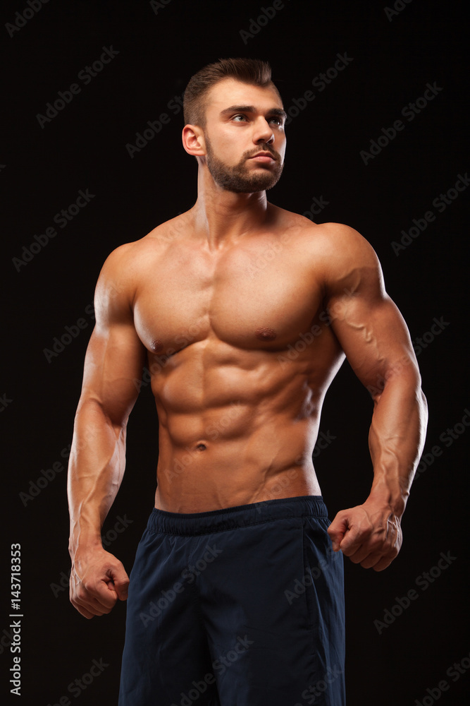 Fototapeta premium Fitness muskularny mężczyzna pozuje i pokazuje jego tors z sześciopakiem abs. pojedynczo na czarnym tle z copyspace