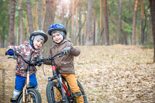 Two little siblings having fun on bikes in autumn or spring forest. Selective focus on boy. © pahis