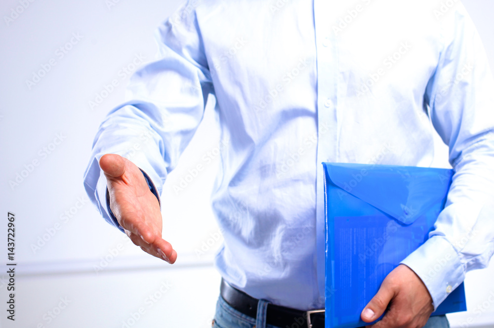 businessman with papers holds out his hand for a handshake