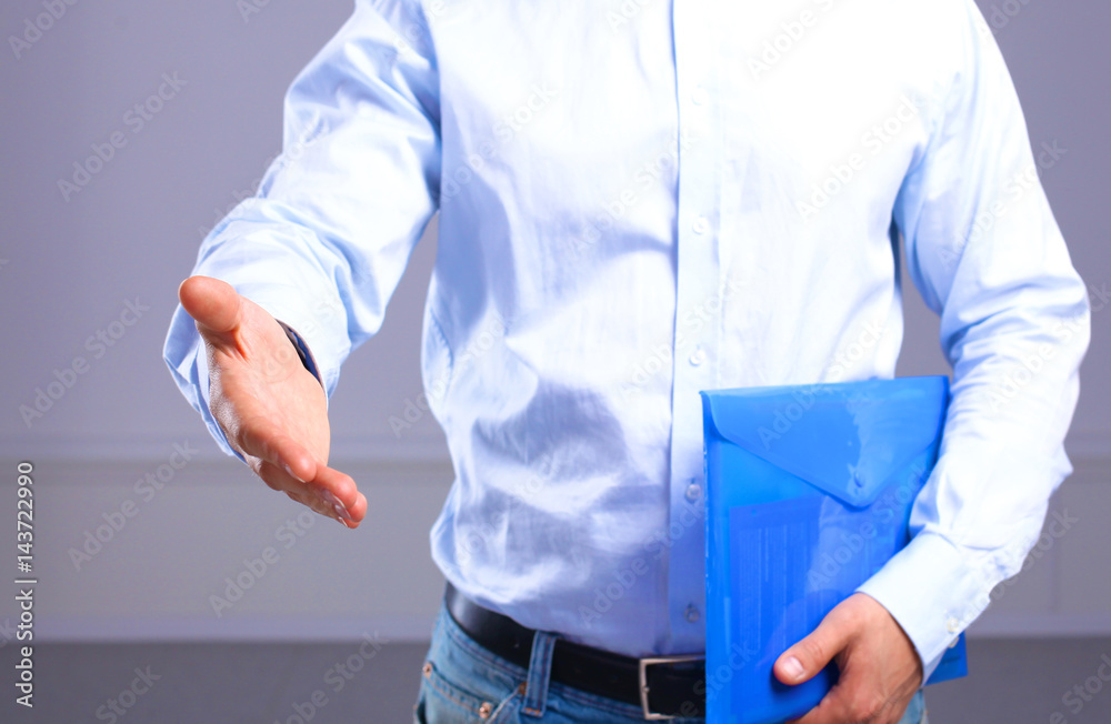 businessman with papers holds out his hand for a handshake