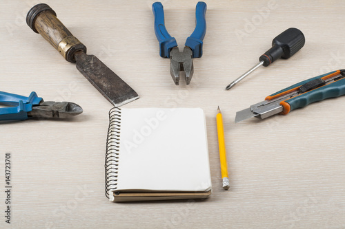 Construction tools, notepad and pencil on wooden background.