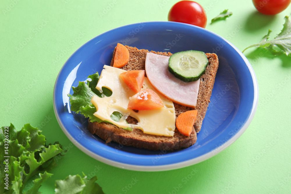 Plate with creative sandwich on green background