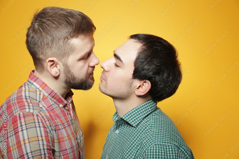 Happy gay couple posing on yellow background Happy gay couple posing on yellow background