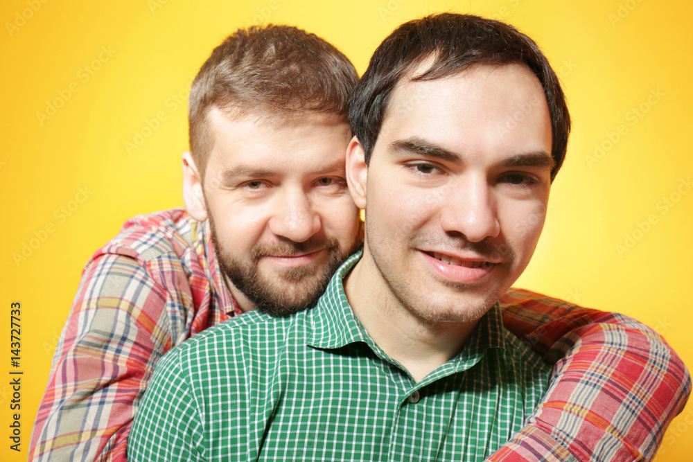 Happy gay couple posing on yellow background Happy gay couple posing on yellow background