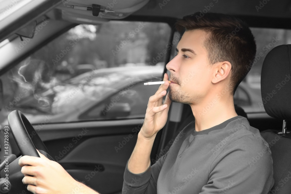 Young man driving a car and smoking cigarette Young man driving a car and smoking cigarette