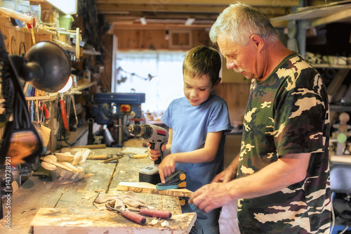 Obraz na plátne grandfather and grandson work with tools in the workshop