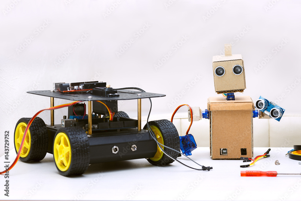 Obraz premium Two robots are on the table, next are the parts for assembling the robot