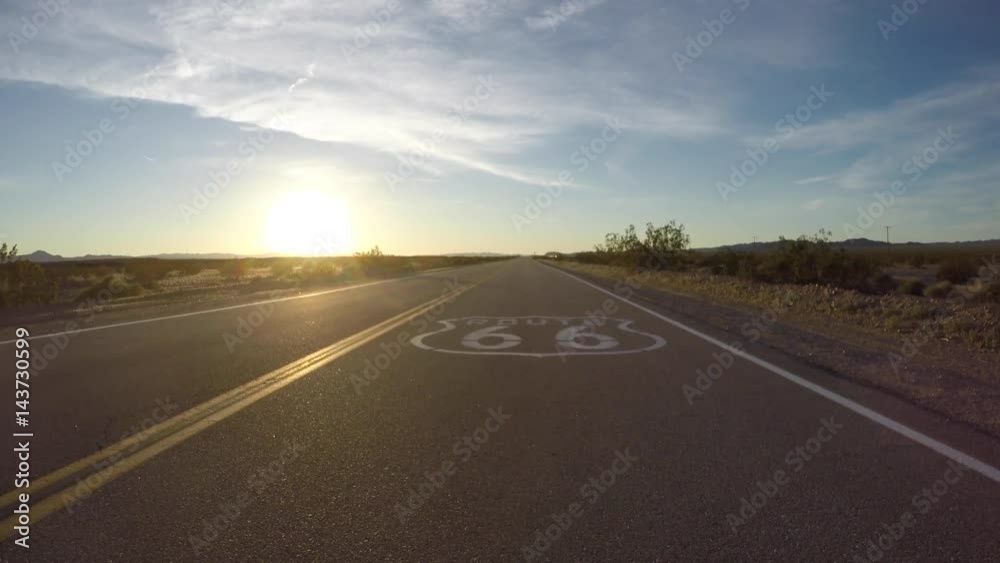 Route 66 pavement sign sunset slow driving shot in the California Mojave Desert.