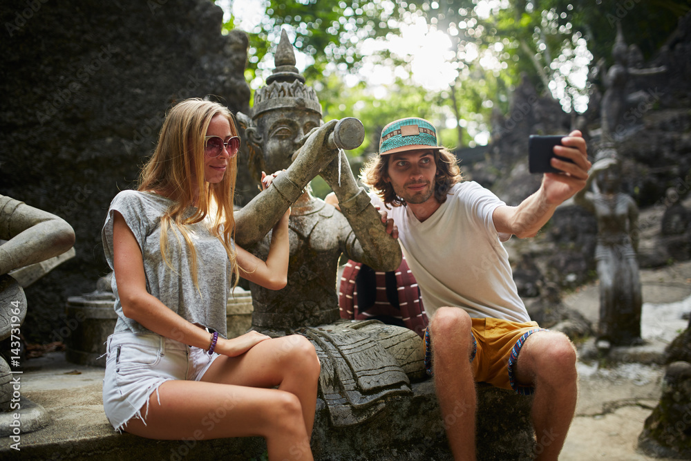 Fototapeta premium tourist couple taking selfie with ancient buddhist statue in thailand