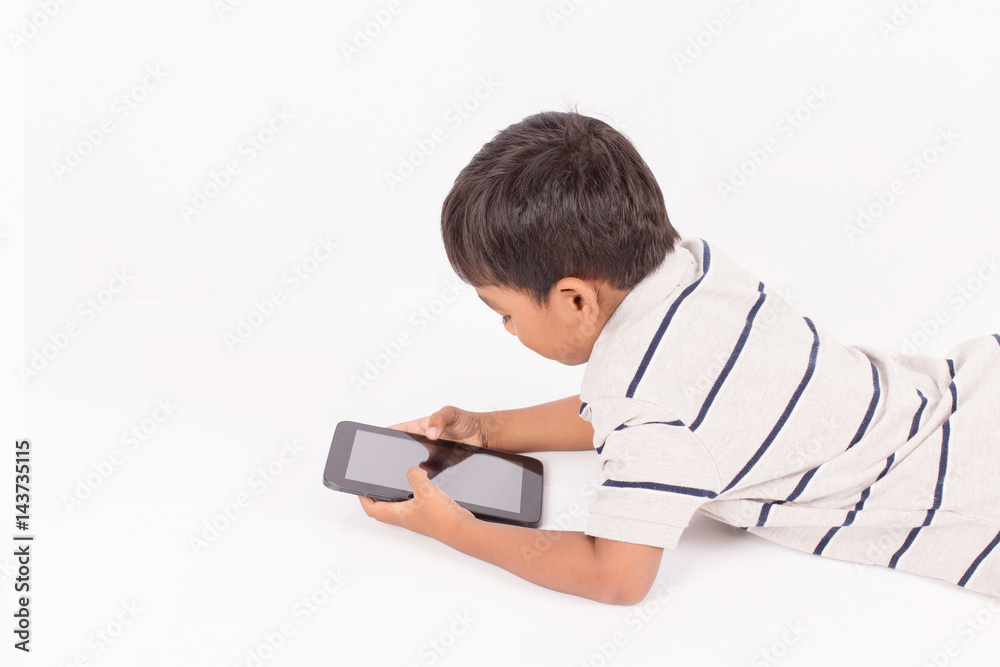 Cute little asian boy lying play tablet on floor