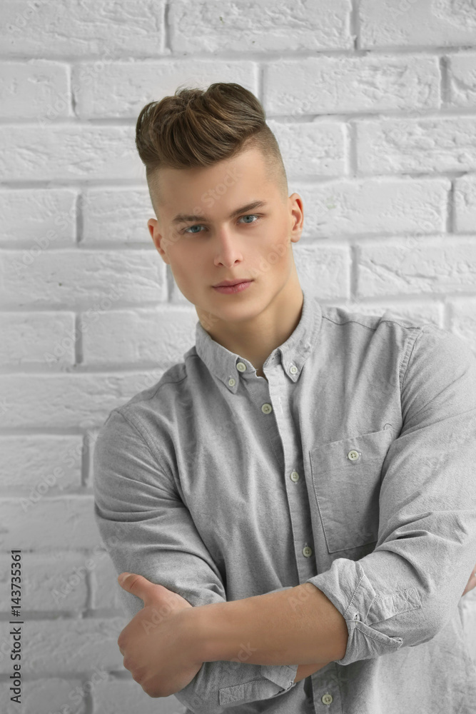 Handsome young man posing on white brick wall background Handsome young man posing on white brick wall background
