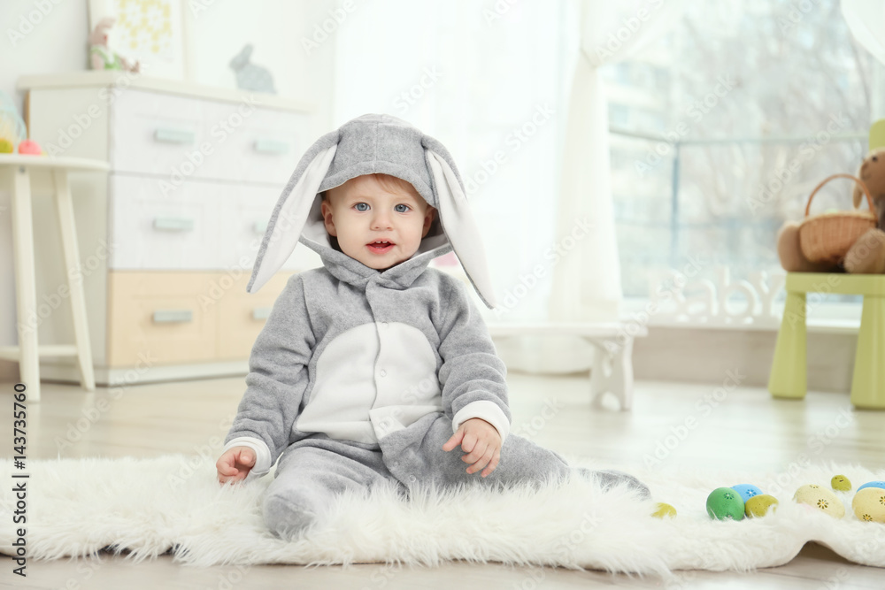 Naklejka premium Cute little baby in bunny costume playing at home