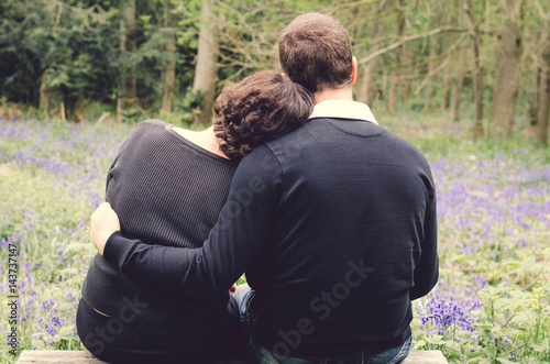 Couple sitting on bench in park. Rear view.
