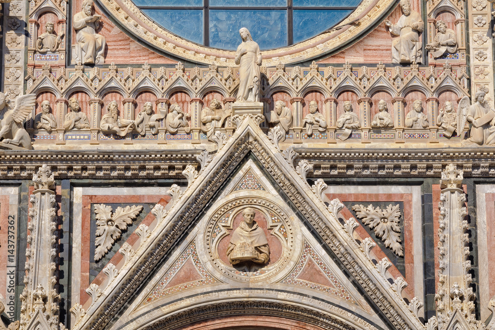 The tympanum of the beautiful marble West facade of the Cathedral Duomo in Siena, Italy