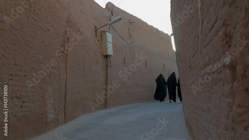 Iranian women in traditional clothes go down the street the old city of Meybod