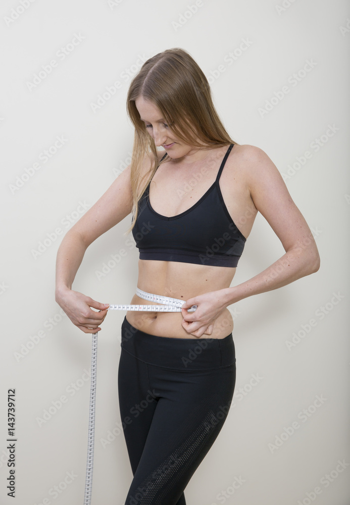 young woman measuring her waist young woman measuring her waist