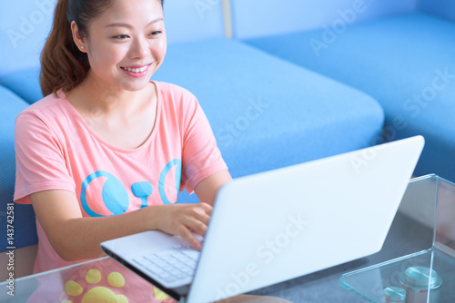 Asian Chinese young woman using laptop in home.