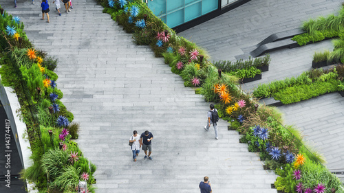 top aerial view people are walking on the bridge pedestrian hardscape and landscape green area garden walkway in the business city area.