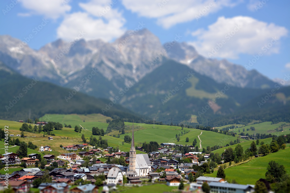Dorf im Salzburger Land, im Hintergrund Gebirgskette mit Wolken